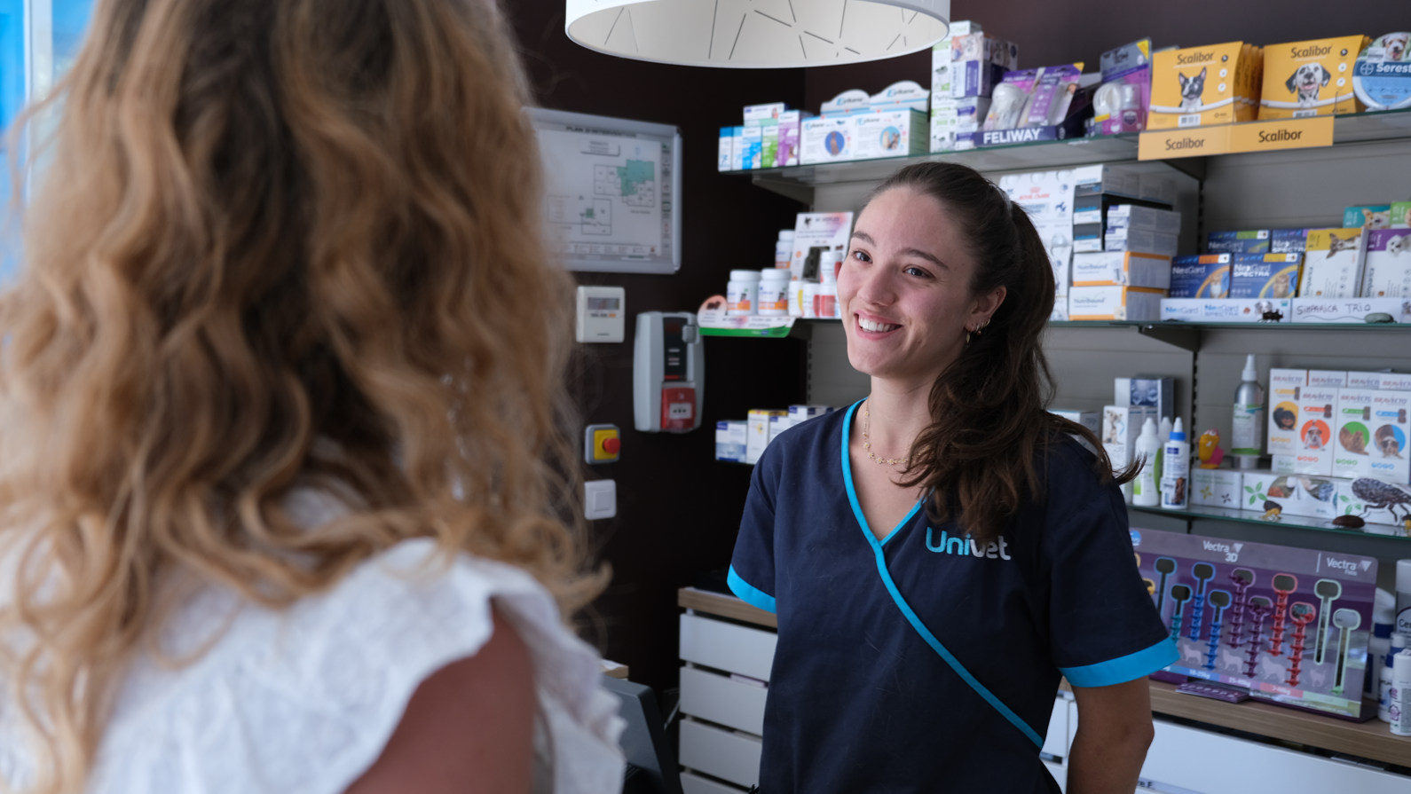 Échange bienveillant entre une propriétaire et une auxiliaire vétérinaire lors d’une visite en clinique
